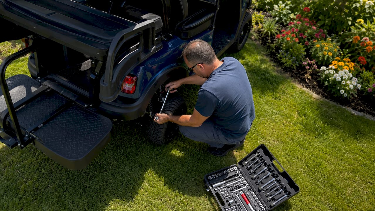 Man adjusting golf cart suspension outdoors