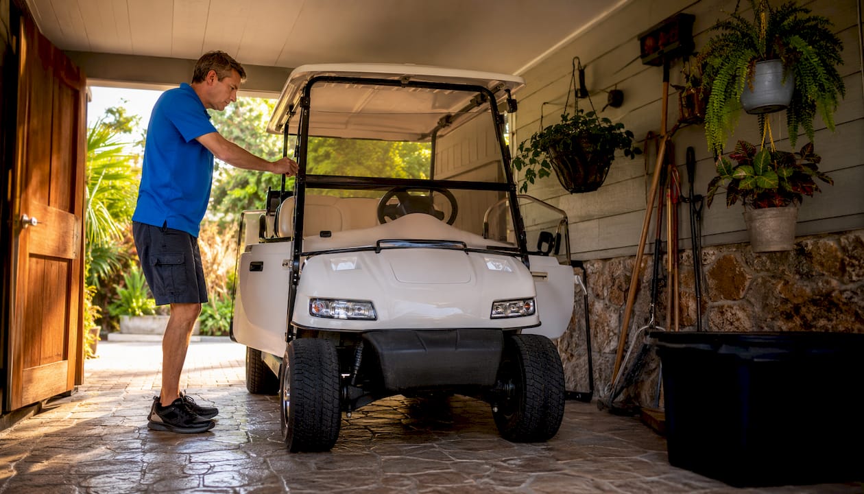 Technician storing golf cart in indoor garage