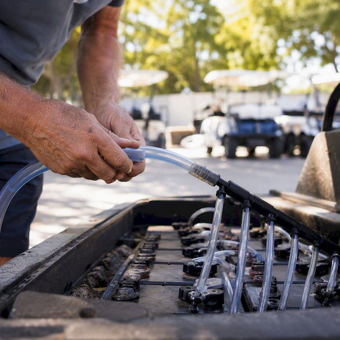 Hands watering golf cart battery cells