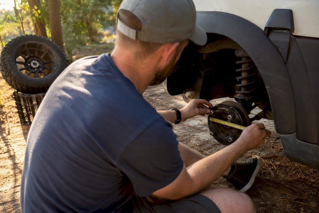 Hands measuring golf cart wheel bolt pattern