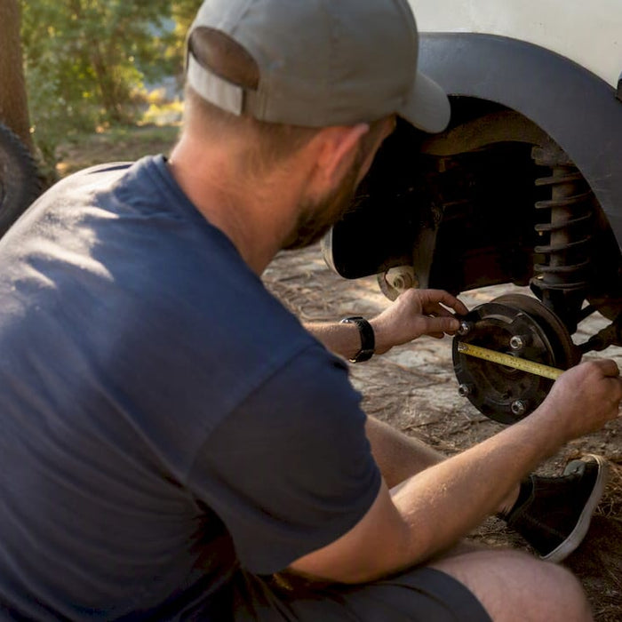 Hands measuring golf cart wheel bolt pattern