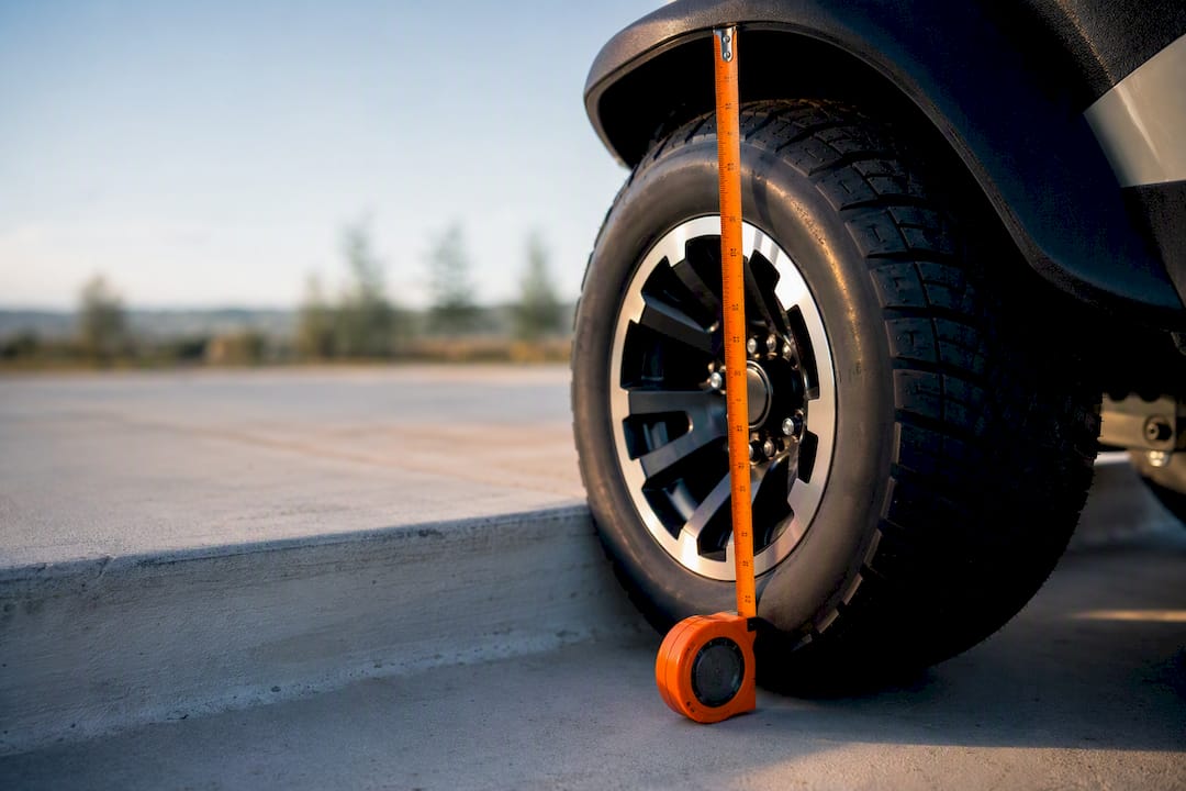 Partial golf cart tire measured beside curb