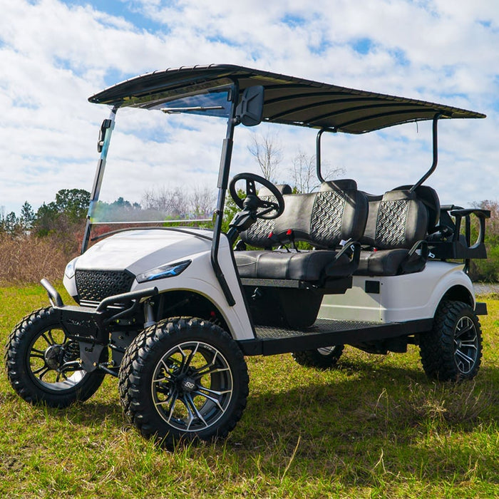 White golf cart with black seats on a grassy area under a blue sky.